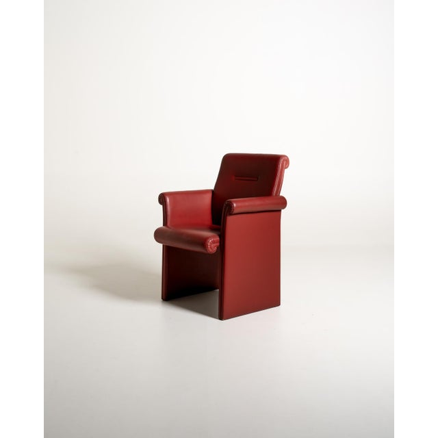 Armchair fully upholstered in red leather, with structural sides, armrests, and distinctive scrolled trim. "Forum Bridge"...