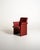 Armchair fully upholstered in red leather, with structural sides, armrests, and distinctive scrolled trim. "Forum Bridge"...