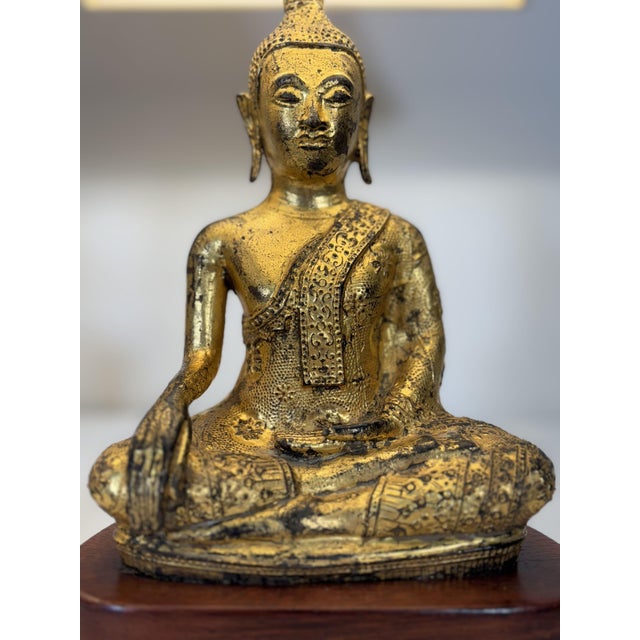 An elegant pair of lamps, each composed of a sculpture of a seated Buddha in meditation, crafted from finely cast and...