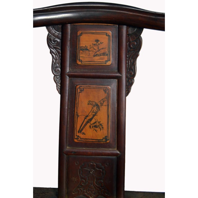 A Chinese hand-carved yumu wood accent yoke back chair with rattan seat, painted scenes and dark brown lacquered finish....