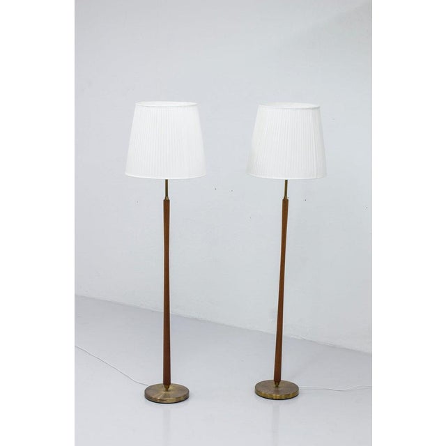 Pair of floor lamps produced in Sweden by ASEA belysning. Made from solid brass and teak stems with a nice concave shape....