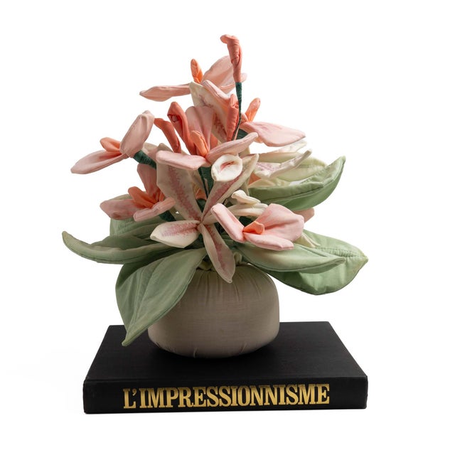Vintage handcrafted fabric floral bouquet in soft shades of pink and peach with green leaves, gathered on an off-white...