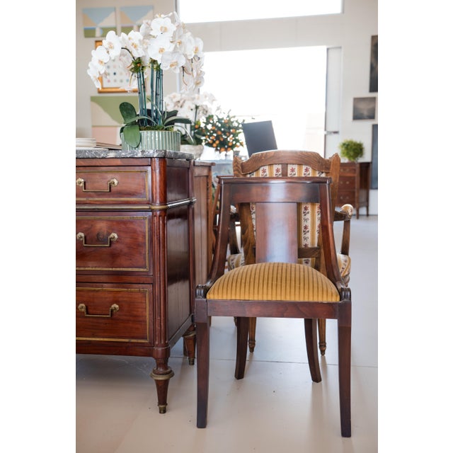 A handsome set of six French Empire–style dining chairs crafted in richly toned walnut, circa 1920. The chairs feature...