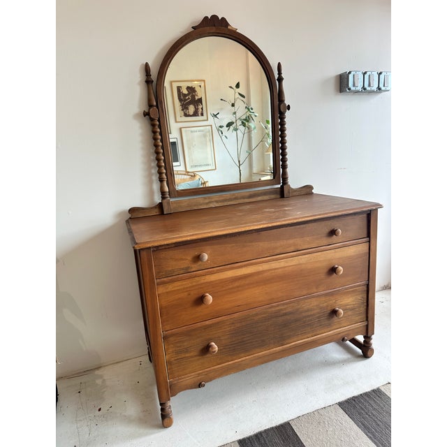 Beautiful antique wooden dresser with an attached mirror, featuring ornate legs and spindle details that give it a classic...