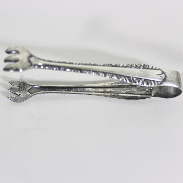 Small vintage silver plated sugar tongs with claw tips. These are ornate. They have tarnish and patina and some wear from...