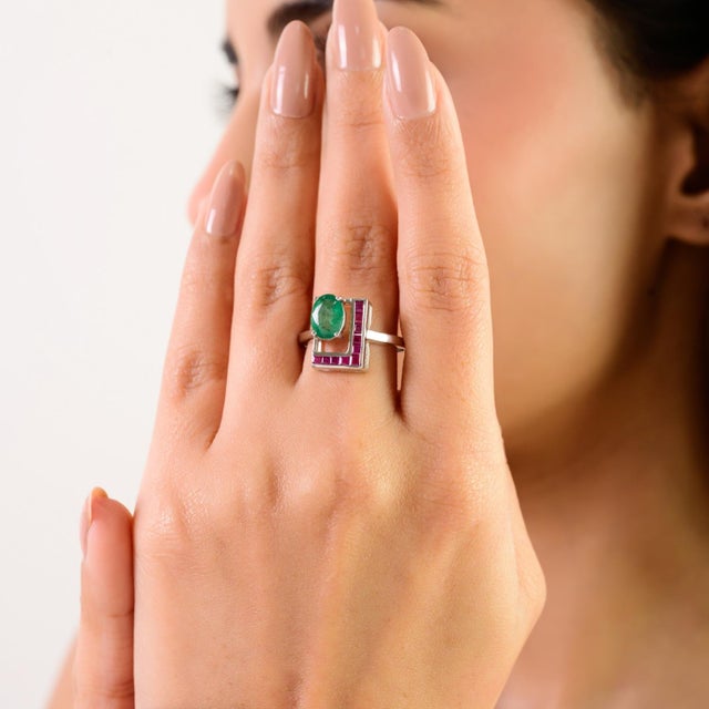 This elegant ring is crafted in sterling silver and features a vibrant oval emerald as its centerpiece, complemented by...