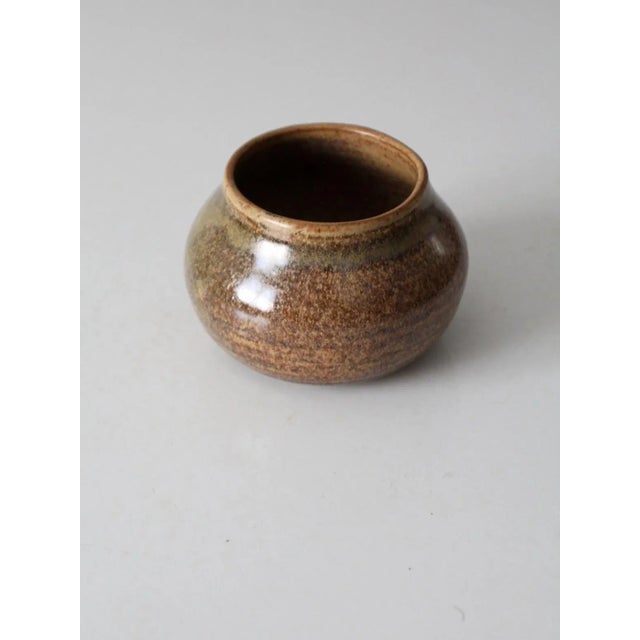 A vintage studio pottery vase signed by the artist, Barrett. The hand-crafted form features a warm two-tone brown speckled...