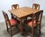 A traditional early 20th century English draw-leaf dining table crafted from quarter sawn oak, paired with a set of four...