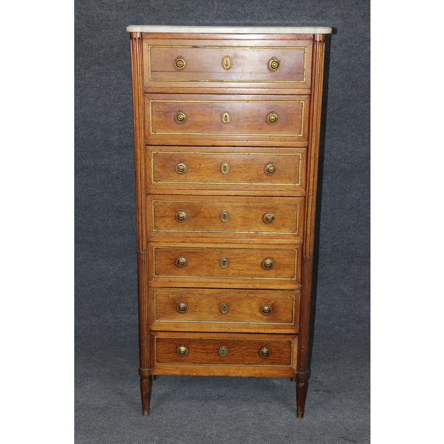 An elegant and beautifully proportioned French Louis XVI style walnut semainier, featuring seven drawers, finely fluted...