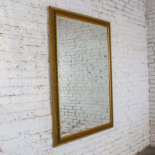 Magnificent vintage Neoclassical to Traditional large sized wall mirror with a rectangular antique gold gilded frame....