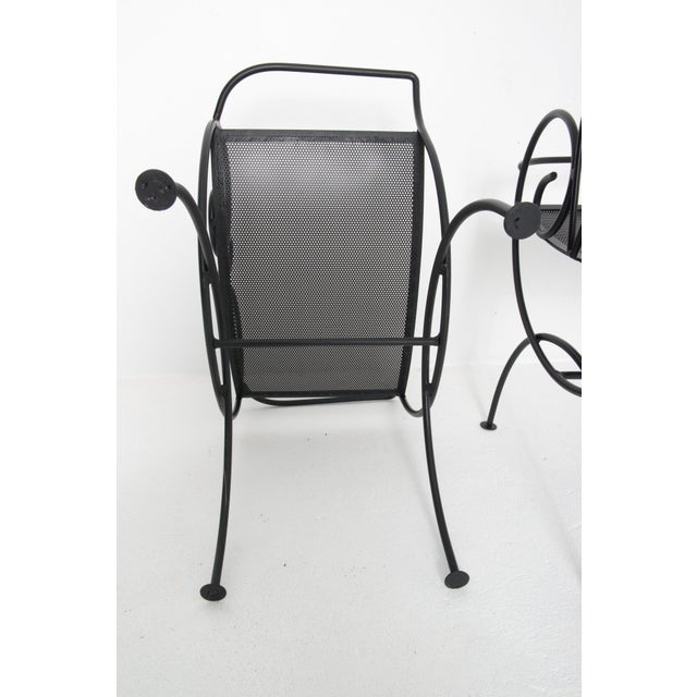 Unusual pair of Salterini style wrought iron benches with low backs and arms. Newly painted black. Pierced sheet metal seats