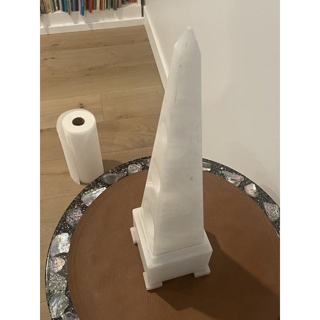 Decorative white marble obelisk with a classic tapered form and polished stone finish. The piece has an architectural,...