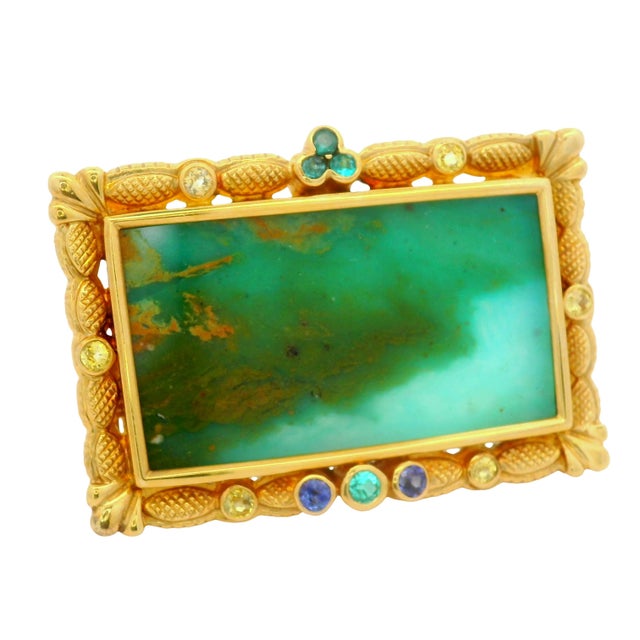 A captivating brooch featuring a portrait opal, showcasing a mesmerizing multi-colored hue, set in 18k yellow gold. The...