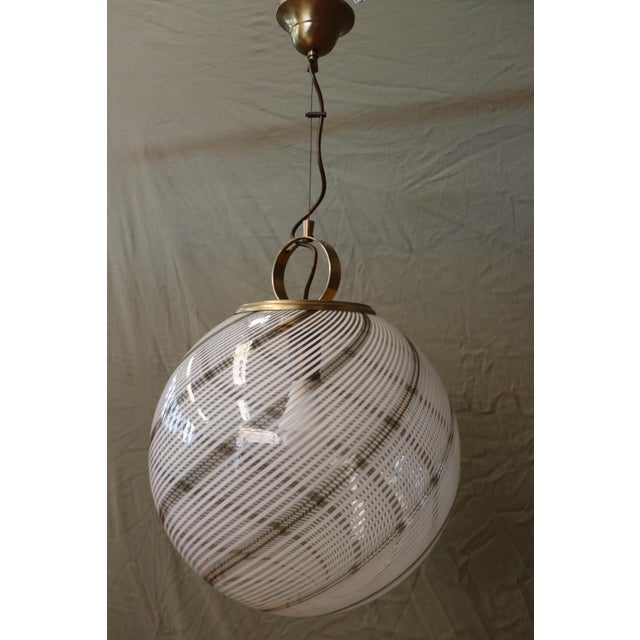 Large round Murano glass pendant light. Vintage 1970s. Decorated with black stripes that follow the shape of the light....