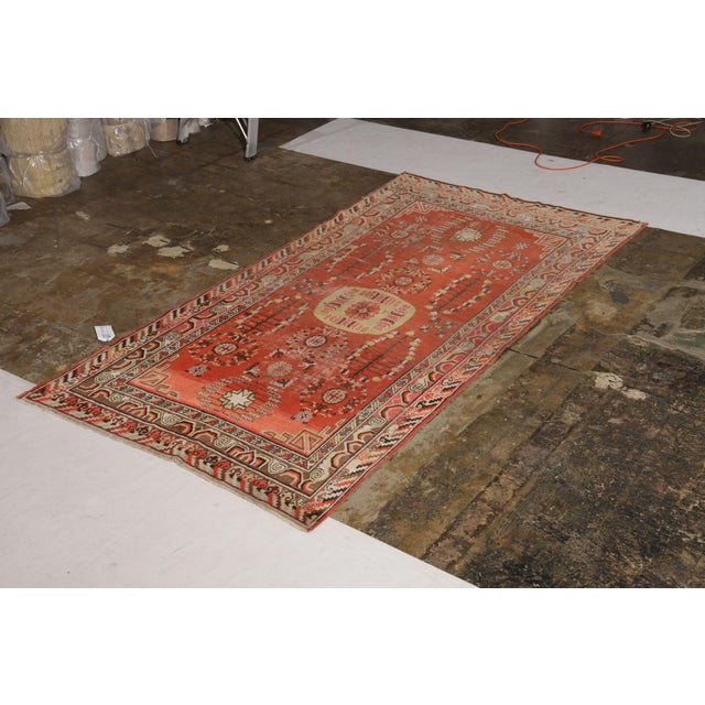 Hand knotted in wool originating from East Turkestan circa 1950-1960, this mid-century piece connotes a vintage Khotan rug...