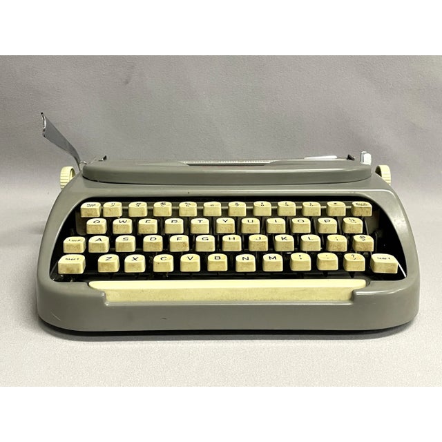 A sweet Singer Scholastic typewriter, made in Holland in 1966. The vintage model T-4 portable typewriter is a gray/green...