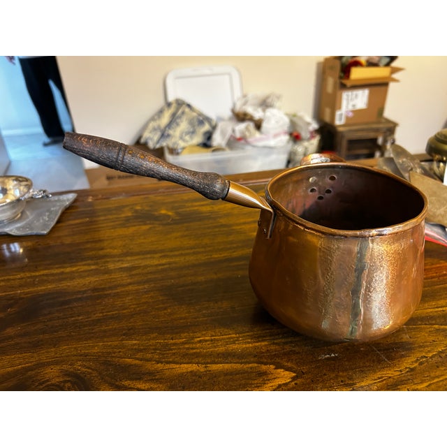 Antique copper poring pot with a wooden handle and spout. Made in Holland. Lovely to add to your kitchen collection of...