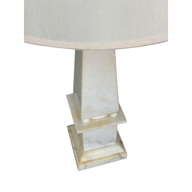 A stunning pair of alabaster marble neoclassical lamps with an obelisk form and ivory linen lamp shades. A beautiful pair...