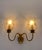 This pair of two-light wall lamps features a polished brass frame, featuring a central oval base from which two curved,...
