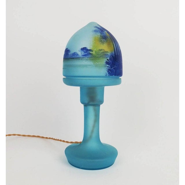 "Mushroom" table lamp made up of two parts in blue tinted glass, wooded landscape decoration on the upper part. French...