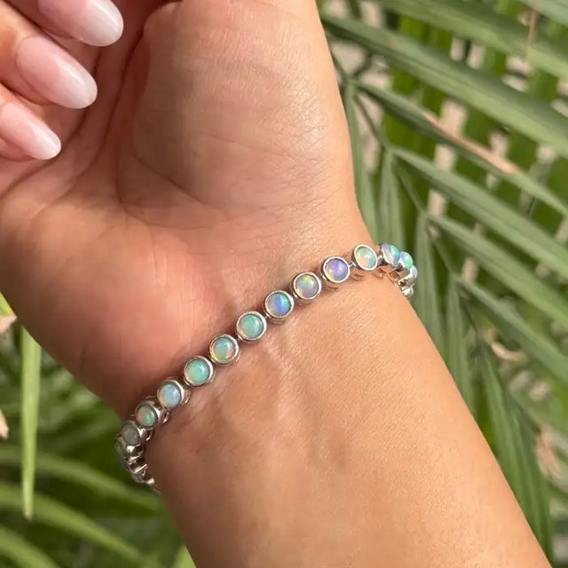 This elegant tennis bracelet is crafted in 925 sterling silver and features 31 round opal gemstones, each measuring 3.8...