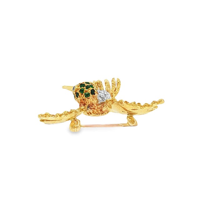 A Mid-century gold hummingbird brooch. Features round green emeralds totaling 0.15 carats. Accented with single-cut white...