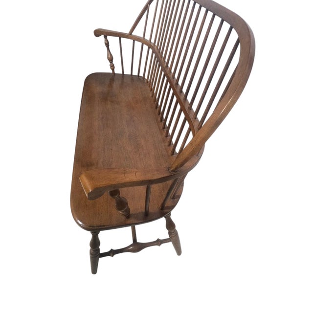 Vintage Windsor-style spindle back bench/settee crafted in solid wood with gracefully curved lines, turned supports, and a...