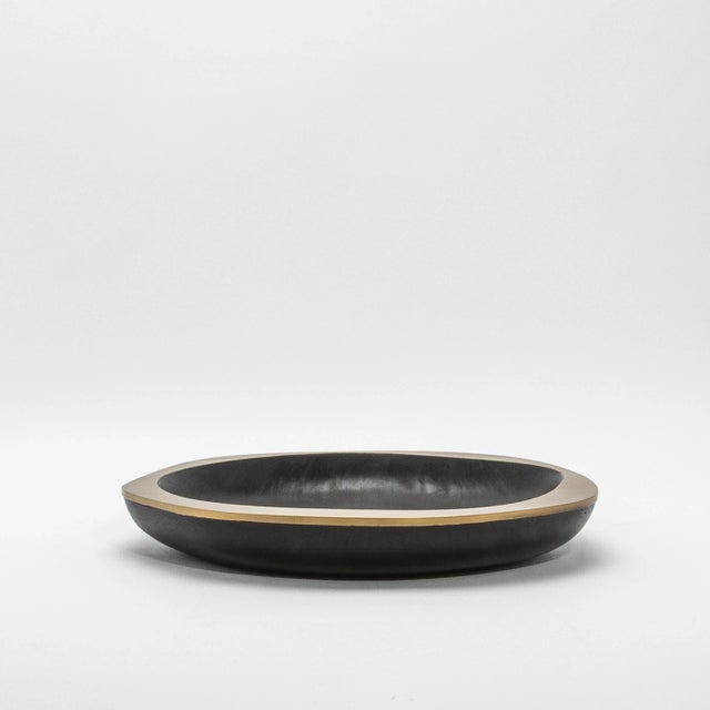 The Lily Bowl in black oak with bronze patina brass details by R&Y Augousti is a stunning embodiment of organic elegance...