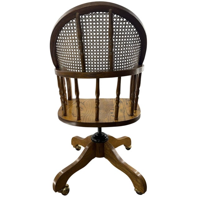 Vintage bentwood swivel desk chair featuring a curved cane backrest, spindle arm supports, and solid wood construction...