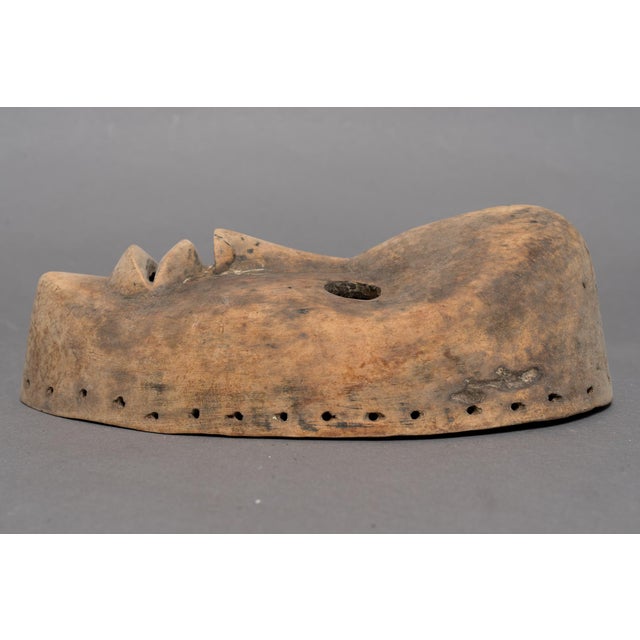 An African hand carved wood mask of Lega, The Democratic Republic of Congo, with a smooth oval face, prominent heart-...