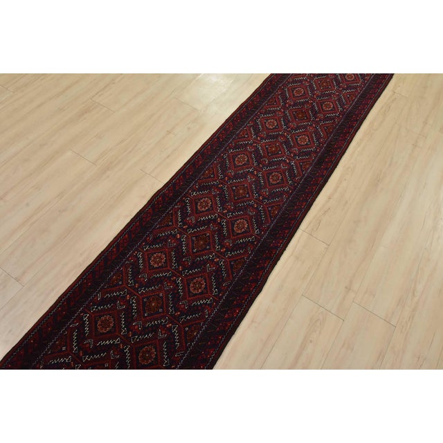 An authentic vintage tribal Baloch runner hand-knotted with fine wool and natural dyes. This nomadic oriental rug features...