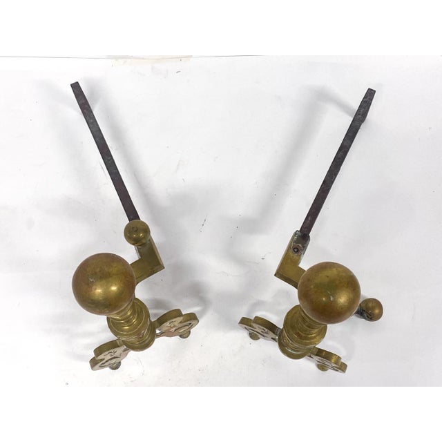 A pair of antique Georgian style brass ball-top andirons with a large sphere finial, multi-ringed turned column, pierced...
