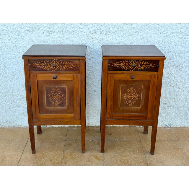 Elegant pair of French bedside cabinets crafted in wood and beautifully decorated with delicate marquetry and contrasting...