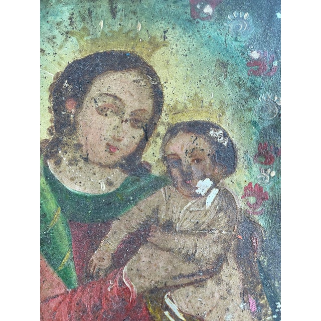 This painted icon showcases the Virgin and Child in a celestial setting, following the traditional Spanish colonial style....