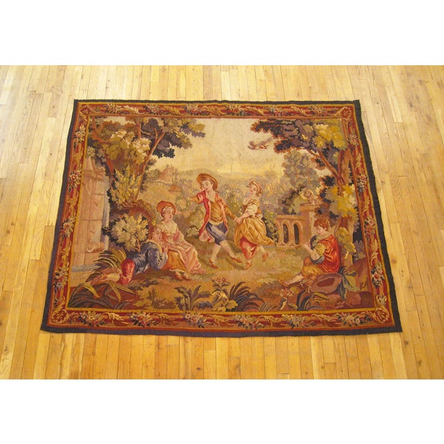 A French Aubusson tapestry from the 19th century, depicting several young courtiers spending a leisurely afternoon gaily...