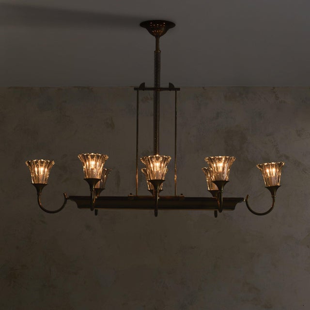An Italian chandelier from the 1940s, pairing luminous glass with the warmth of brass. Eight curved arms extend from a...