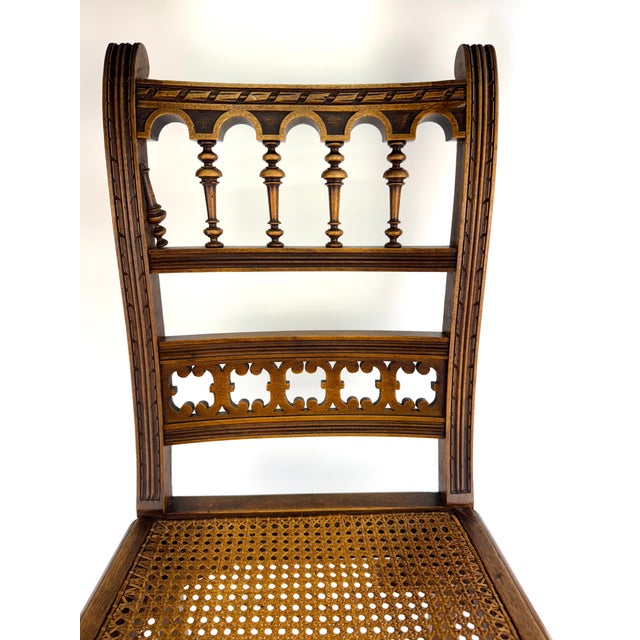 A finely detailed Eastlake-style chair in warm walnut, featuring a hand-caned seat and an intricately carved back with...