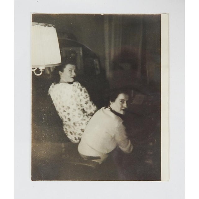 1950's vernacular snapshot photograph of two women sitting and looking back. Unframed, has been trimmed.