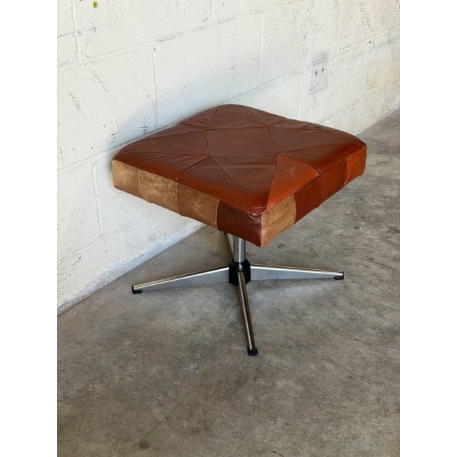 This square ottoman features a striking patchwork top over a minimalist tubular frame. The bold geometric design creates...