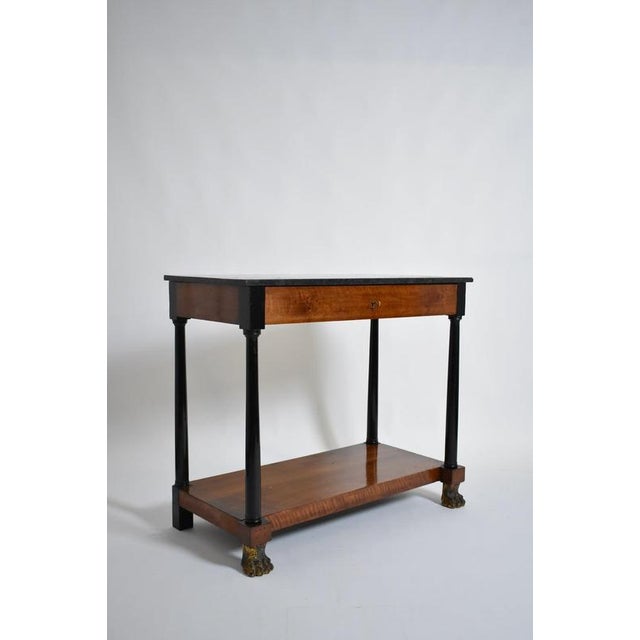 Consulate period lion paws console, XIXth c. Console table, side table, in light wood veneer and blackened wood opening to...