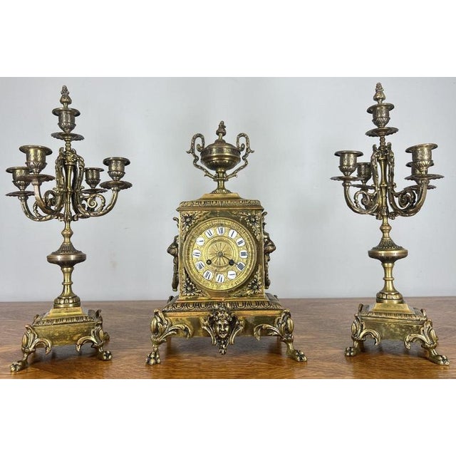 This elegant Vintage French clock garniture set features a beautifully detailed central clock flanked by a matching pair...