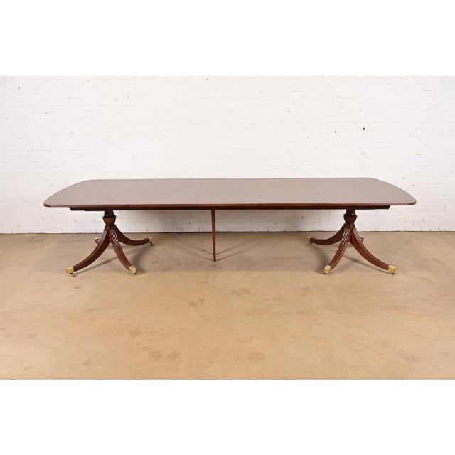 An exceptional Georgian or Regency style double pedestal extension dining table By Smith & Watson USA, Circa 1960s...