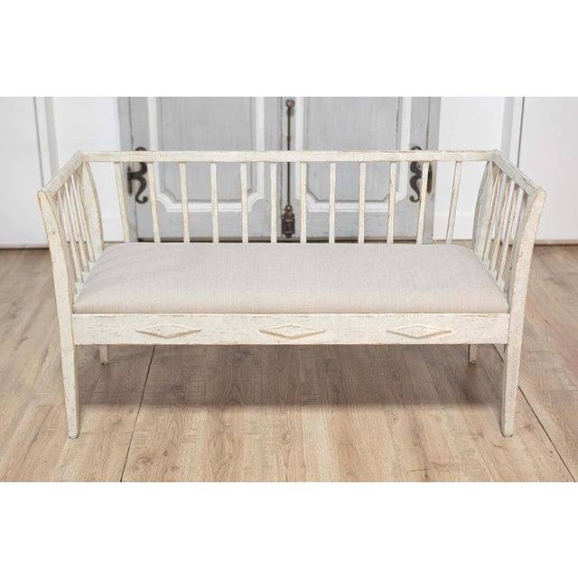 A Swedish Gustavian style gray painted sofa bench from the 20th century with high back, raised diamond motifs and linen...