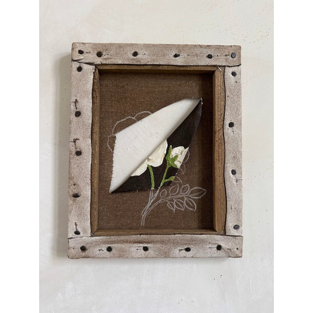 The artwork features a delicate floral composition that emerges from a textured background, creating a sense of depth and...