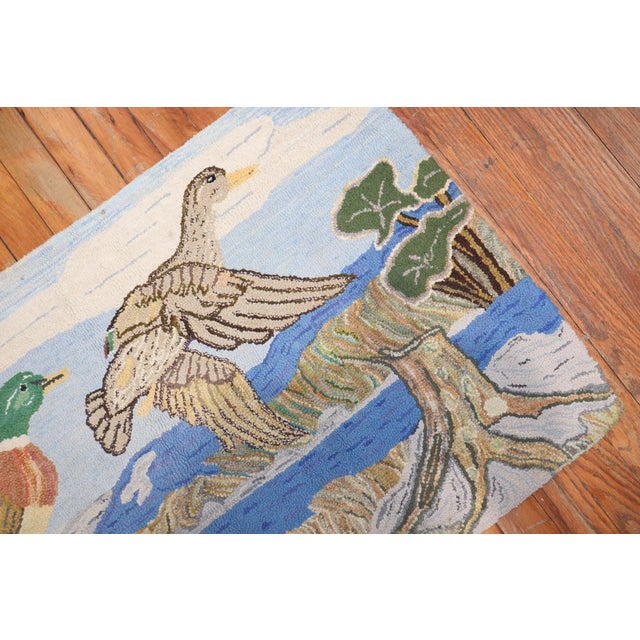 A handmade decorative American hooked rug from the middle of the 20th century depicting 2 ducks on a lively scenic view....