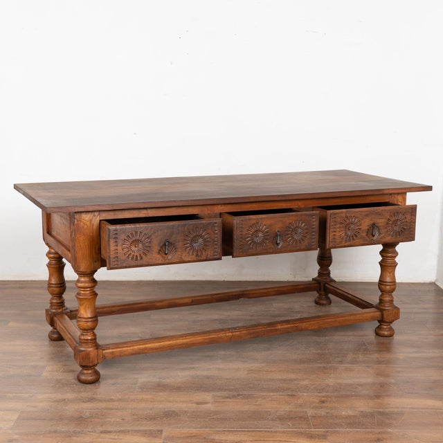 Dark walnut console table just under 7' long with three drawers resting on turned legs and stretcher base. Note the deep...