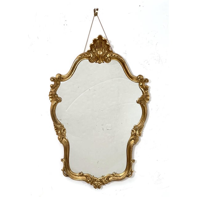A fine English gilt wall mirror in the Rococo Revival style, featuring a beautifully gilded carved design around the...