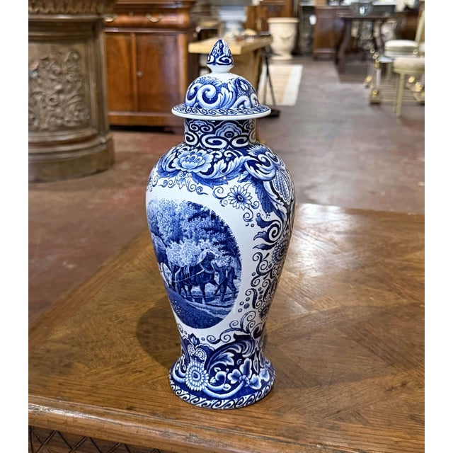Featuring traditional Dutch countryside scenes and intricate floral decoration, this vintage Delft-style covered vase was...