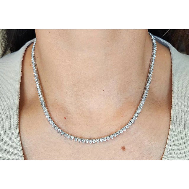 This necklace showcases a sleek design with a continuous line of 160 diamonds. The primary stones are round cut, totaling...