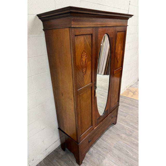 This is a stunning antique Edwardian mahogany wardrobe dating to the early 20th century. Features a striking oval mirror...
